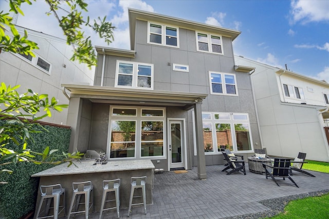 3116 Somerset Levens Ln, Houston, TX 77055 - back of property featuring a fire pit, a patio area, and stucco siding
