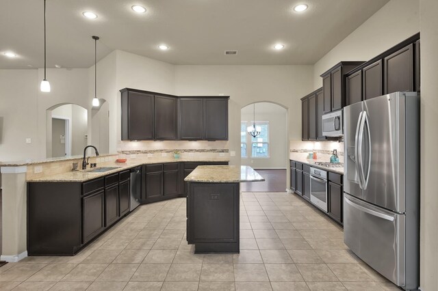 7610 Willow School Dr, Spring, TX 77389 - kitchen with appliances with stainless steel finishes, arched walkways, backsplash, light stone counters, and a kitchen island