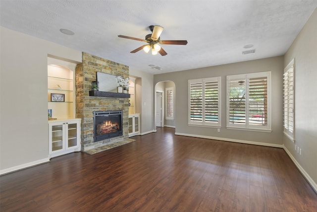 17310 Calico Peak Way, Cypress, TX 77433 - unfurnished living room with wood finished floors, ceiling fan, a fireplace, a textured ceiling, and arched walkways