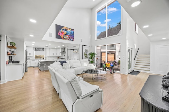 5122 Glenmeadow Dr, Houston, TX 77096 - living room featuring light wood-style floors, stairs, recessed lighting, and a towering ceiling