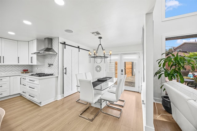 5122 Glenmeadow Dr, Houston, TX 77096 - kitchen with wall chimney exhaust hood, a barn door, tasteful backsplash, white cabinetry, and recessed lighting