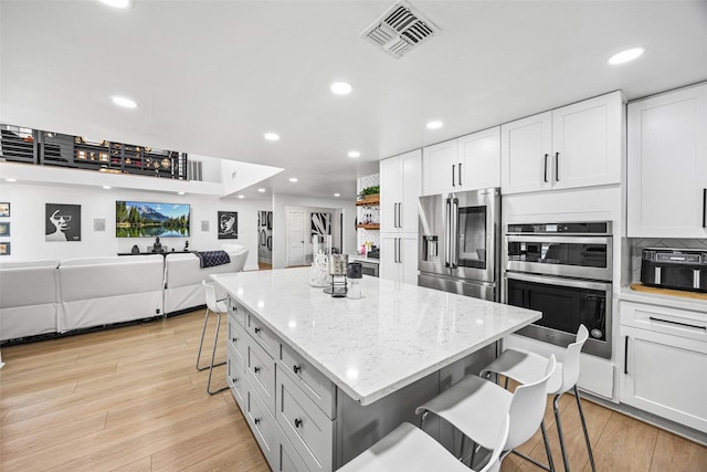 5122 Glenmeadow Dr, Houston, TX 77096 - kitchen with stainless steel appliances, a breakfast bar area, open floor plan, recessed lighting, and white cabinetry