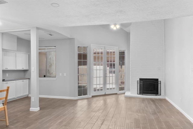668 N Eldridge Pkwy, Houston, TX 77079 - unfurnished living room with wood finished floors, a textured ceiling, a brick fireplace, and lofted ceiling