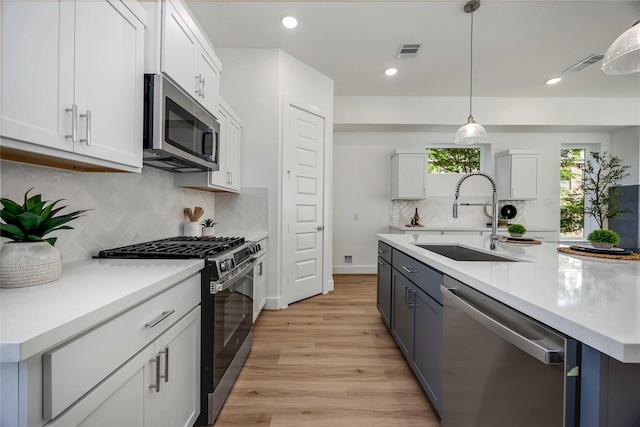 4415 Caroline St, Houston, TX 77004 - kitchen featuring appliances with stainless steel finishes, light countertops, light wood-type flooring, white cabinets, and backsplash