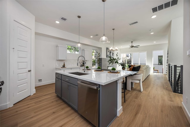 4415 Caroline St, Houston, TX 77004 - kitchen featuring stainless steel dishwasher, light wood-type flooring, light countertops, open floor plan, and backsplash