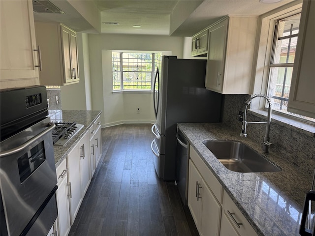 8446 Cabot St, Houston, TX 77078 - kitchen featuring stainless steel appliances, tasteful backsplash, dark wood-type flooring, light stone countertops, and white cabinetry