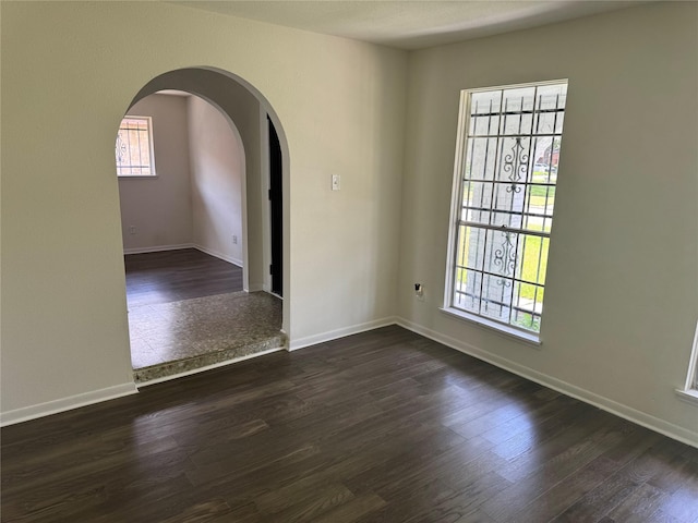 8446 Cabot St, Houston, TX 77078 - empty room featuring arched walkways and dark wood-type flooring