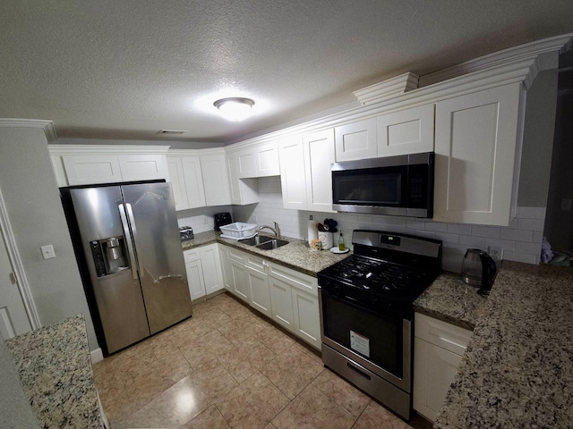 6227 Cavalier St Unit 770, Houston, TX 77087 - kitchen featuring appliances with stainless steel finishes, tasteful backsplash, white cabinets, light stone countertops, and a textured ceiling
