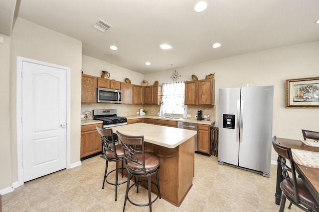 3811 Rosalind Ln, Houston, TX 77053 - kitchen with appliances with stainless steel finishes, brown cabinets, light countertops, a kitchen bar, and recessed lighting