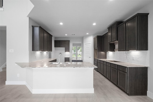 3040 Mesquite Pod Trl, Conroe, TX 77301 - kitchen with a peninsula, light stone countertops, tasteful backsplash, and recessed lighting