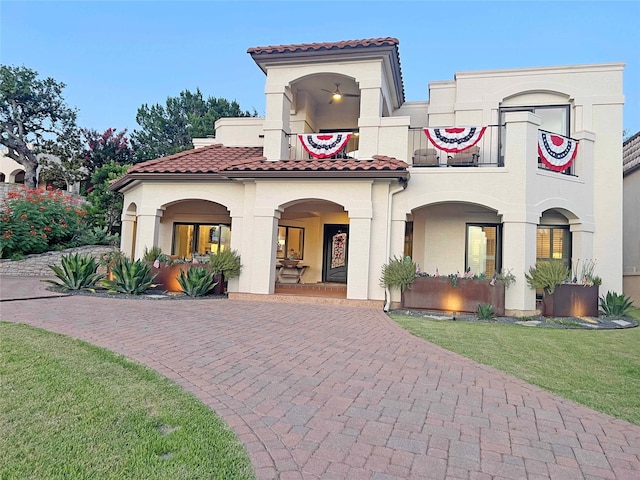 1234 Challenger, Lakeway, TX 78734 - mediterranean / spanish-style home featuring a tiled roof, curved driveway, a balcony, a front yard, and stucco siding