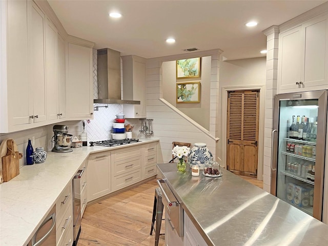 1234 Challenger, Lakeway, TX 78734 - kitchen featuring stainless steel countertops, wall chimney range hood, stainless steel gas stovetop, light wood-style flooring, and backsplash