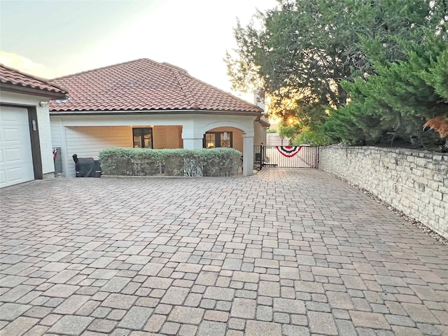 1234 Challenger, Lakeway, TX 78734 - view of property exterior featuring decorative driveway, a gate, a tiled roof, and stucco siding