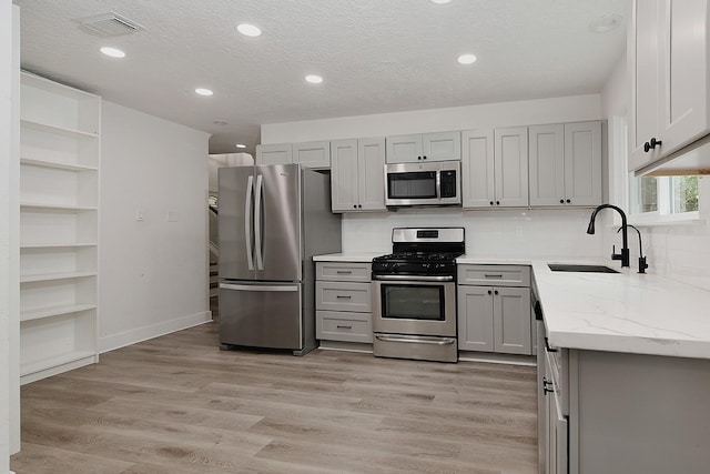 3 Meadow Beauty, The Woodlands, TX 77381 - kitchen featuring appliances with stainless steel finishes, gray cabinetry, open shelves, light stone countertops, and recessed lighting