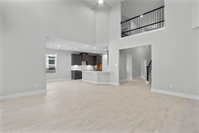 1912 Golden Spruce Ln, Conroe, TX 77301 - unfurnished living room with stairway, light wood-style floors, ceiling fan, a high ceiling, and recessed lighting