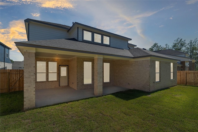 1912 Golden Spruce Ln, Conroe, TX 77301 - back of house at dusk with a patio, brick siding, and roof with shingles