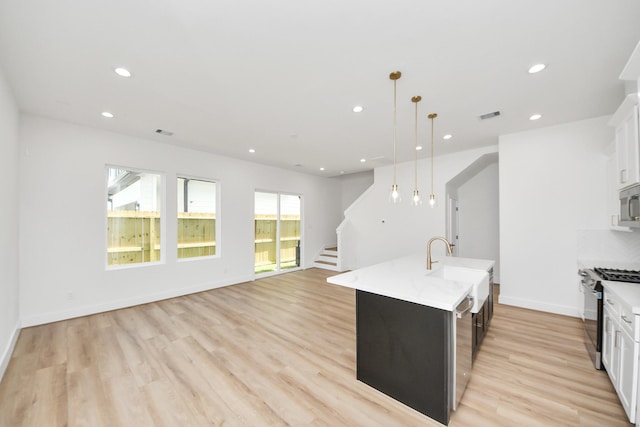 103 Frawley St, Houston, TX 77009 - kitchen with appliances with stainless steel finishes, light countertops, recessed lighting, a center island with sink, and light wood-style flooring