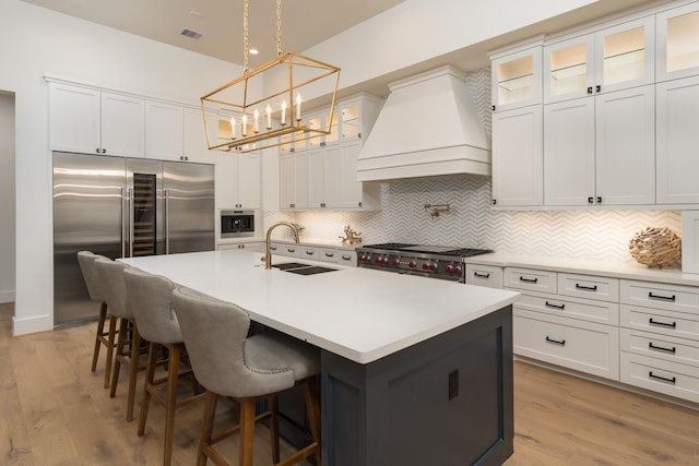 512 W Alkire Lake Dr, Sugar Land, TX 77478 - kitchen featuring custom range hood, high end appliances, a chandelier, decorative backsplash, and light wood-type flooring