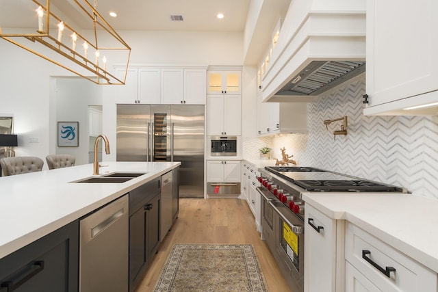 512 W Alkire Lake Dr, Sugar Land, TX 77478 - kitchen featuring premium appliances, custom range hood, white cabinets, and recessed lighting