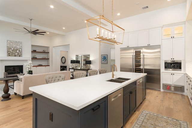 512 W Alkire Lake Dr, Sugar Land, TX 77478 - kitchen with stainless steel appliances, white cabinets, a kitchen island with sink, a warming drawer, and recessed lighting