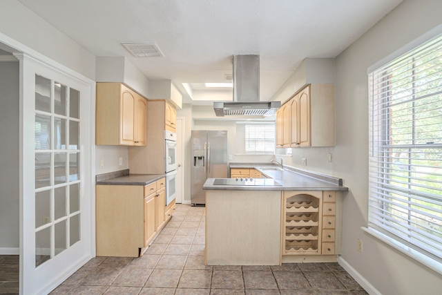 5606 Water Leaf Ln, Houston, TX 77088 - kitchen featuring island exhaust hood, light brown cabinetry, stainless steel fridge, and double oven
