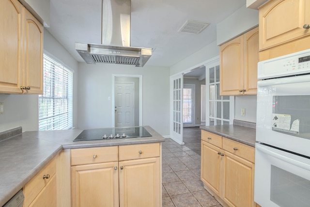 5606 Water Leaf Ln, Houston, TX 77088 - kitchen with light brown cabinets, wall chimney exhaust hood, white double oven, black electric stovetop, and a peninsula