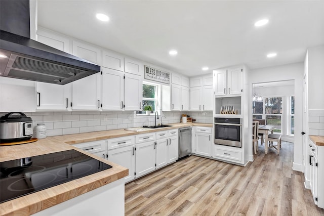 17207 Hill View Ln, Spring, TX 77379 - kitchen with butcher block countertops, stainless steel appliances, wall chimney exhaust hood, tasteful backsplash, and light wood finished floors