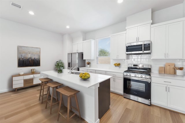 1013 Erin St Unit W, Houston, TX 77009 - kitchen with stainless steel appliances, light wood-style flooring, tasteful backsplash, a kitchen breakfast bar, and recessed lighting