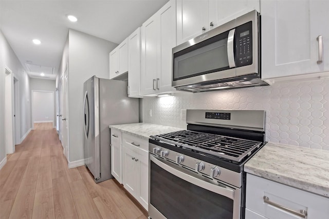 411 E 37th St, Houston, TX 77018 - kitchen featuring appliances with stainless steel finishes, white cabinetry, light wood finished floors, light stone countertops, and tasteful backsplash