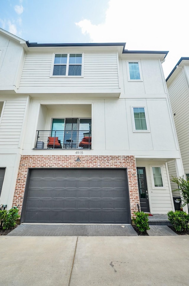4915 Ave J, Houston, TX 77011 - townhome / multi-family property featuring an attached garage, brick siding, driveway, stucco siding, and a balcony