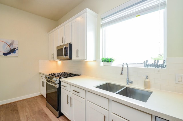 4915 Ave J, Houston, TX 77011 - kitchen featuring stainless steel appliances, tasteful backsplash, light wood finished floors, white cabinets, and light countertops