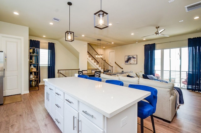 4915 Ave J, Houston, TX 77011 - kitchen featuring a kitchen island, open floor plan, white cabinets, a ceiling fan, and light wood-style floors