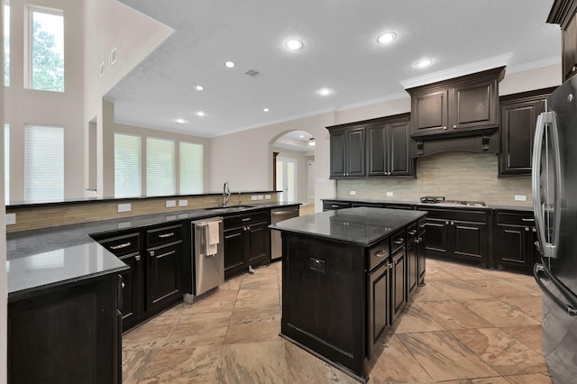 3403 Wooded Ln, Conroe, TX 77301 - kitchen with stainless steel appliances, arched walkways, a center island, crown molding, and backsplash