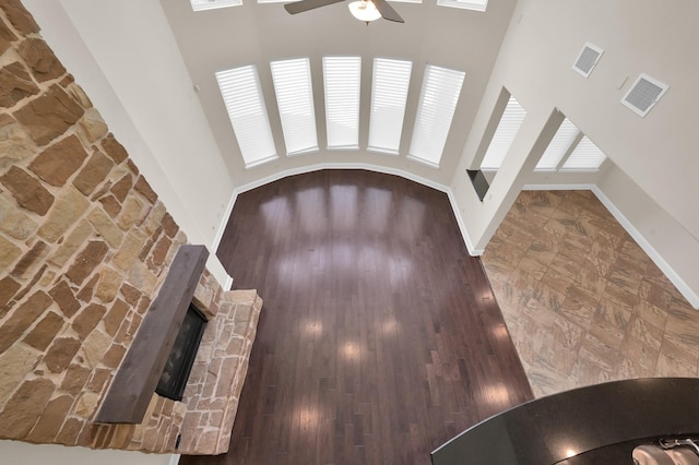 3403 Wooded Ln, Conroe, TX 77301 - unfurnished living room with ceiling fan, a high ceiling, a stone fireplace, and wood finished floors