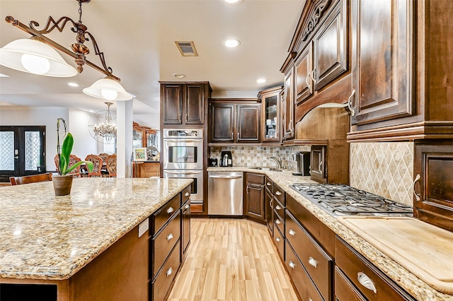 3022 Triway Ln, Houston, TX 77043 - kitchen with stainless steel appliances, light stone counters, recessed lighting, light wood finished floors, and decorative backsplash