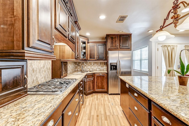 3022 Triway Ln, Houston, TX 77043 - kitchen featuring appliances with stainless steel finishes, light stone countertops, crown molding, light wood finished floors, and decorative backsplash