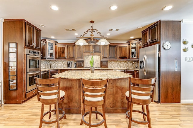 3022 Triway Ln, Houston, TX 77043 - kitchen featuring stainless steel appliances, glass insert cabinets, a kitchen island, light wood-style flooring, and recessed lighting