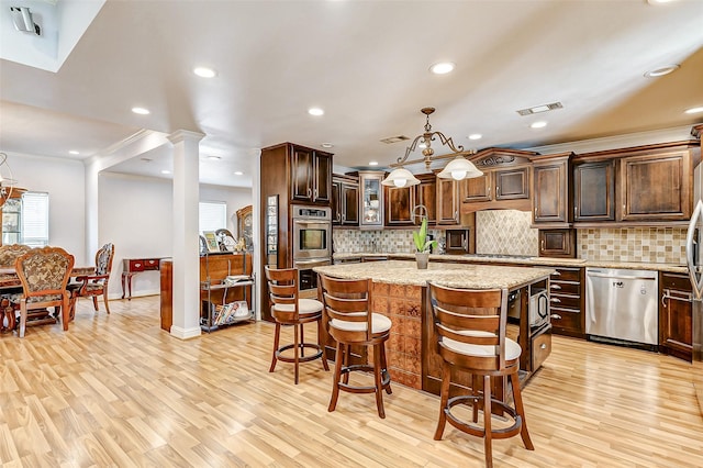 3022 Triway Ln, Houston, TX 77043 - kitchen with stainless steel appliances, a kitchen island, light wood finished floors, dark brown cabinetry, and light stone counters