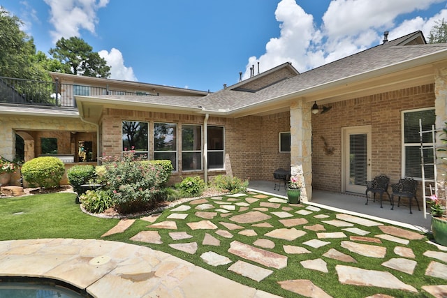 7826 Camden Hollow Ln, Humble, TX 77396 - back of house featuring a patio, brick siding, a balcony, roof with shingles, and a lawn