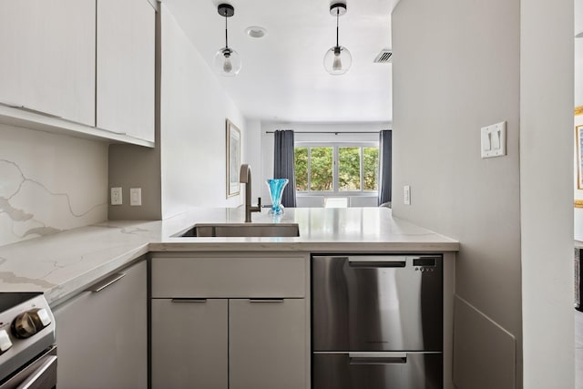 3600 Montrose Blvd Unit 209, Houston, TX 77006 - kitchen with stainless steel appliances, light stone countertops, white cabinetry, a peninsula, and decorative light fixtures