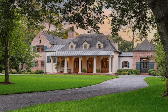 3 E Rivercrest Dr, Houston, TX 77042 - view of front of house featuring a standing seam roof, french doors, a porch, a front yard, and a chimney