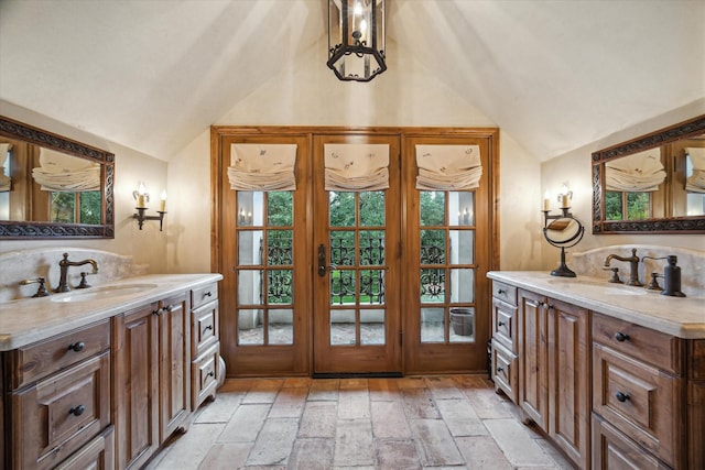 3 E Rivercrest Dr, Houston, TX 77042 - bathroom featuring vaulted ceiling, two vanities, french doors, and stone tile floors