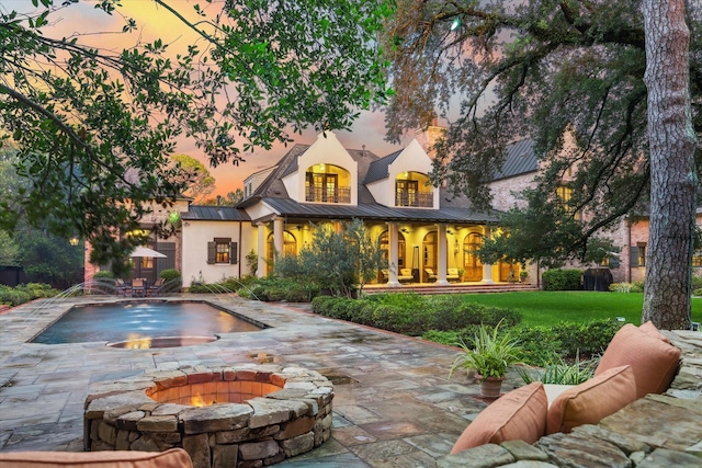 3 E Rivercrest Dr, Houston, TX 77042 - back of property with a standing seam roof, stucco siding, a metal roof, a fire pit, and a yard
