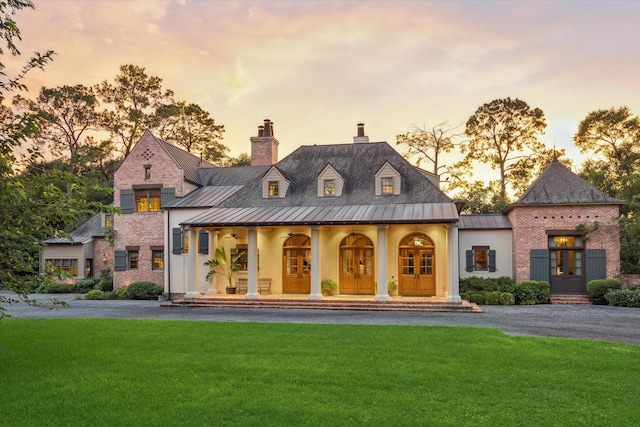 3 E Rivercrest Dr, Houston, TX 77042 - view of front of house featuring a standing seam roof, a front lawn, covered porch, a chimney, and a metal roof