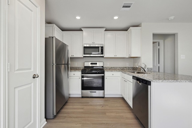 396 Tejas Trl, Waller, TX 77484 - kitchen featuring appliances with stainless steel finishes, white cabinets, light wood-style flooring, recessed lighting, and light stone counters