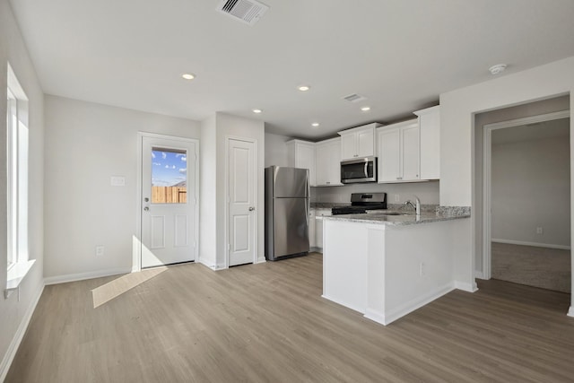 396 Tejas Trl, Waller, TX 77484 - kitchen featuring appliances with stainless steel finishes, light wood-type flooring, white cabinetry, a peninsula, and recessed lighting