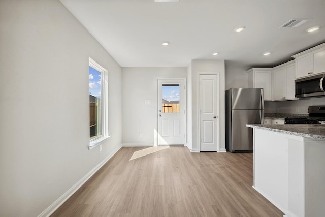 396 Tejas Trl, Waller, TX 77484 - kitchen featuring appliances with stainless steel finishes, light wood-style floors, stone counters, white cabinets, and recessed lighting