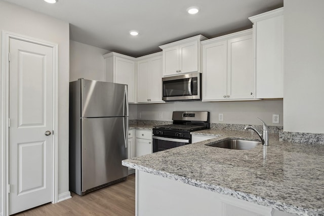 396 Tejas Trl, Waller, TX 77484 - kitchen featuring stainless steel appliances, white cabinets, light stone counters, light wood-type flooring, and recessed lighting