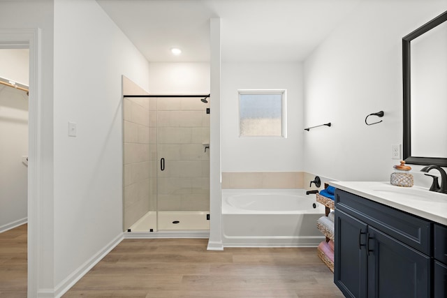 10722 Sky Creek Ln, Beasley, TX 77417 - full bathroom featuring vanity, a shower stall, a garden tub, wood finished floors, and a walk in closet