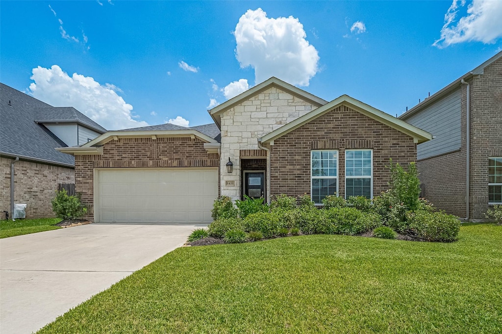 8439 Oakland Heights Ln, Richmond, TX 77407 - view of front of property with a garage, a front lawn, driveway, brick siding, and stone siding